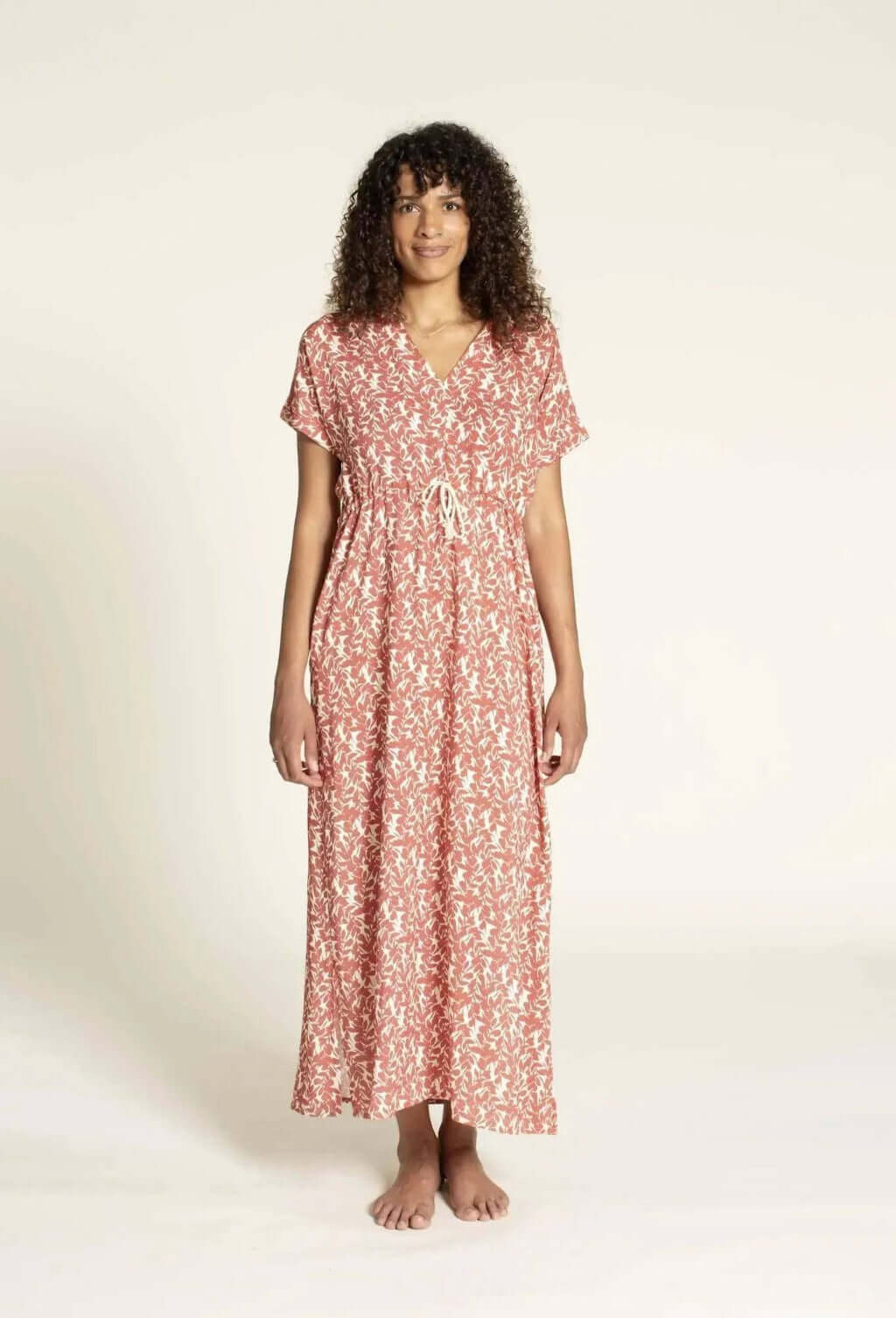 Model wearing the Abby Dress sewing pattern, a relaxed kaftan-style dress with floral print and tie waist detail.