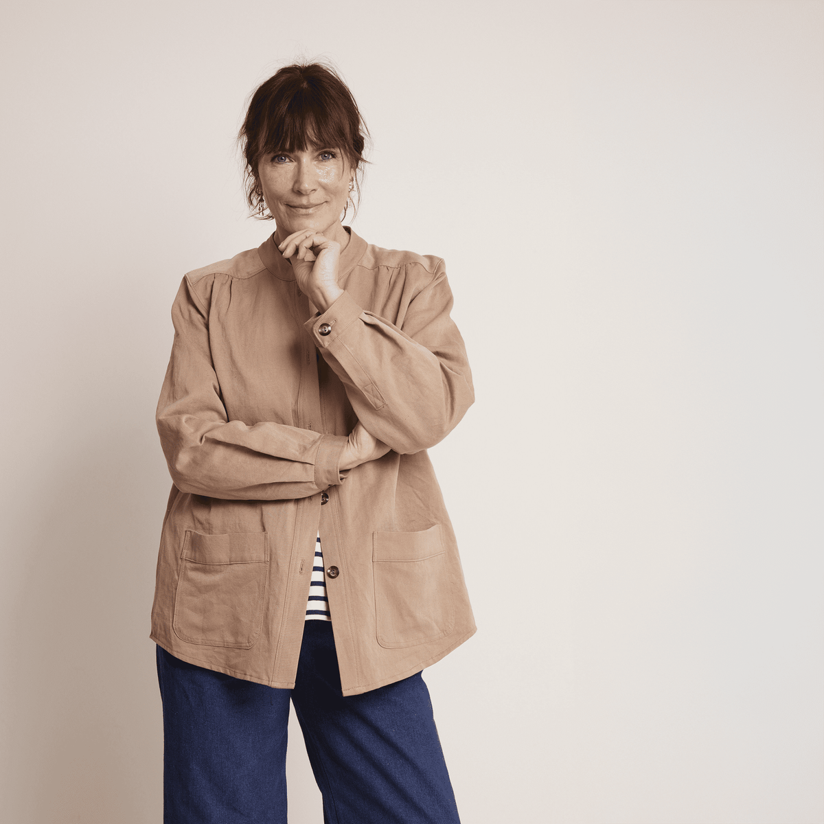 A woman wearing a relaxed Artist Jacket Paper Pattern in light brown, featuring large patch pockets and a minimalist design.
