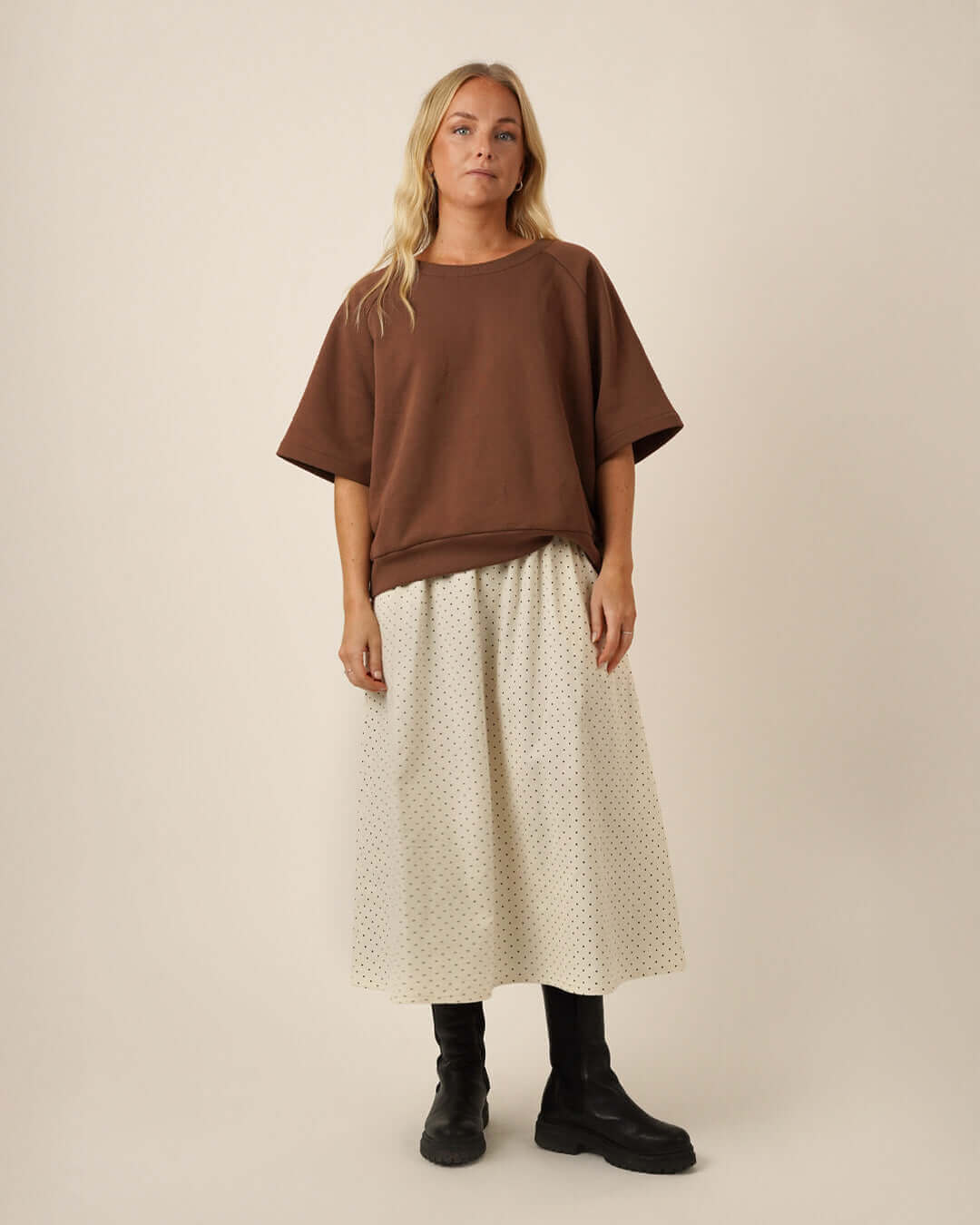 Woman wearing a brown Boxy Sweater sewing pattern, and a white Claude skirt sewing pattern