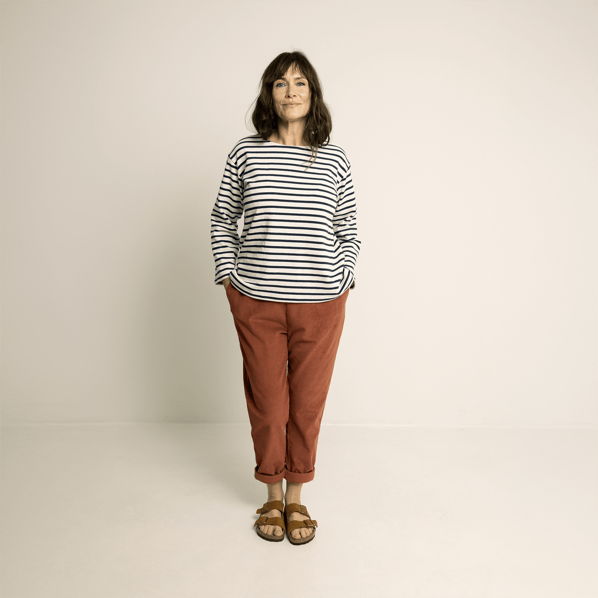 Woman wearing striped shirt and relaxed-fit Easy Pants Paper Pattern in red standing against a neutral background.