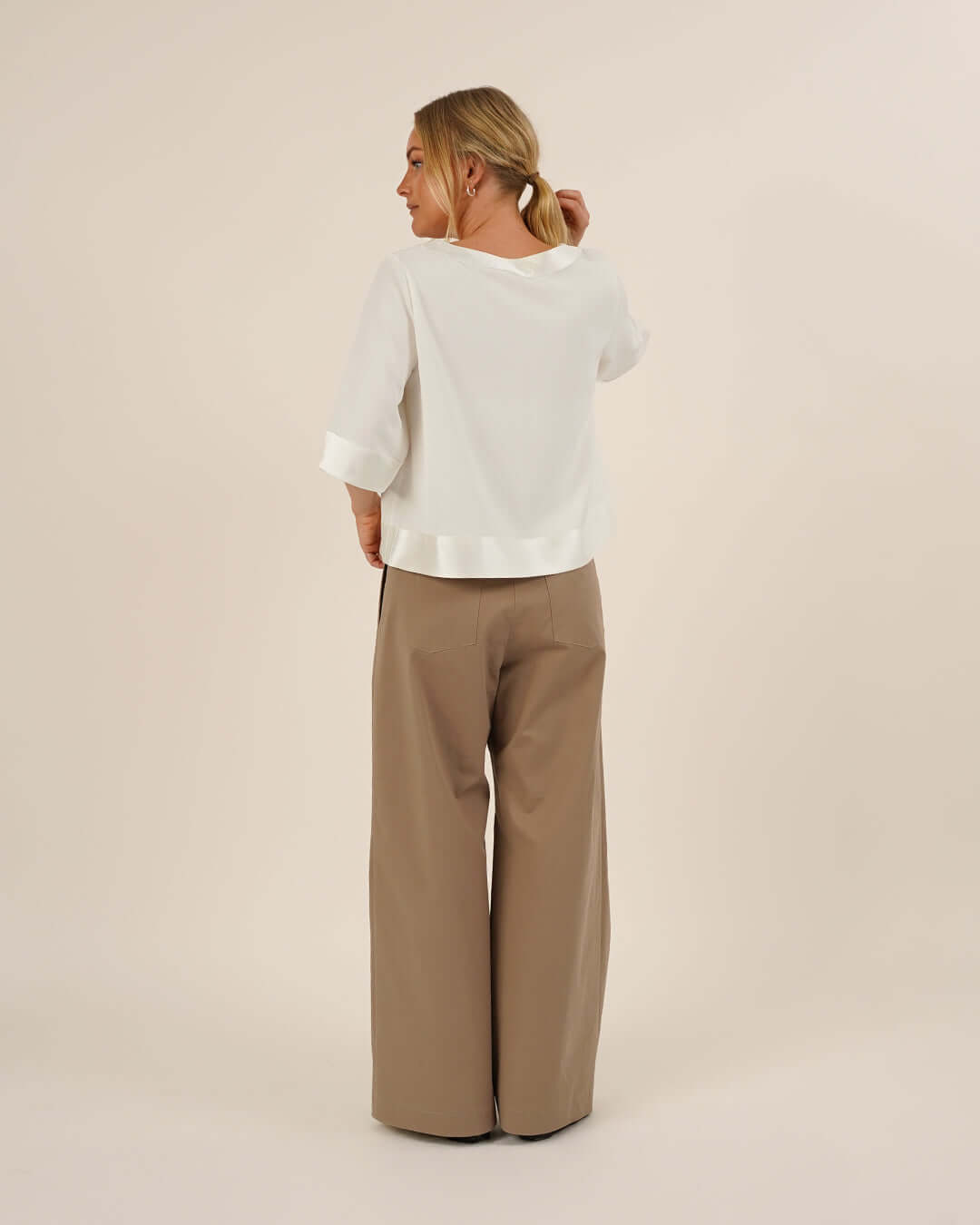Woman wearing the Silke Blouse sewing pattern in white silk and a pair of Bermuda Pants