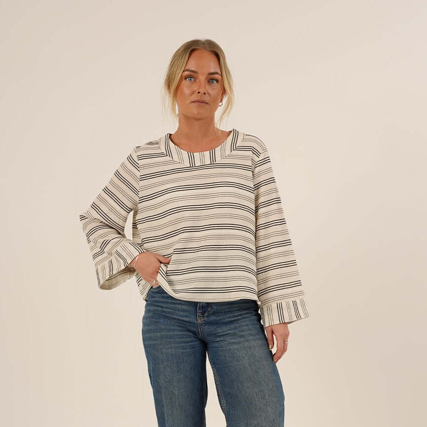 Woman wearing the Silke Blouse sewing pattern black and white stribes and a pair of Jeans