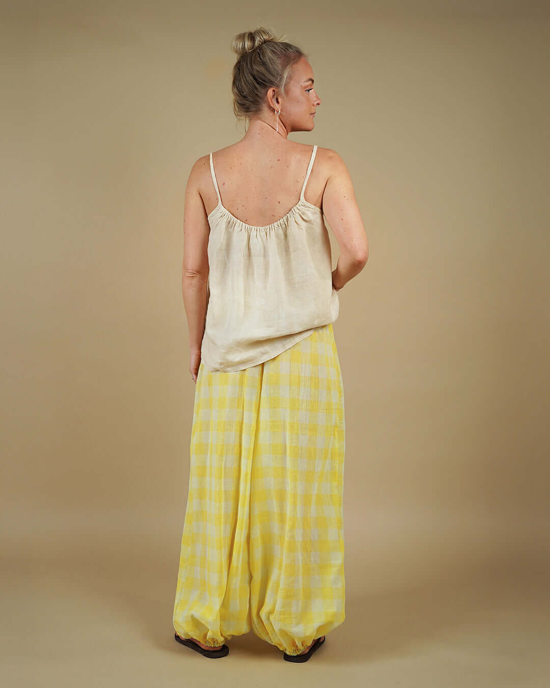 Back view of a woman wearing the Skagen Dress sewing pattern top with yellow checkered pants.
