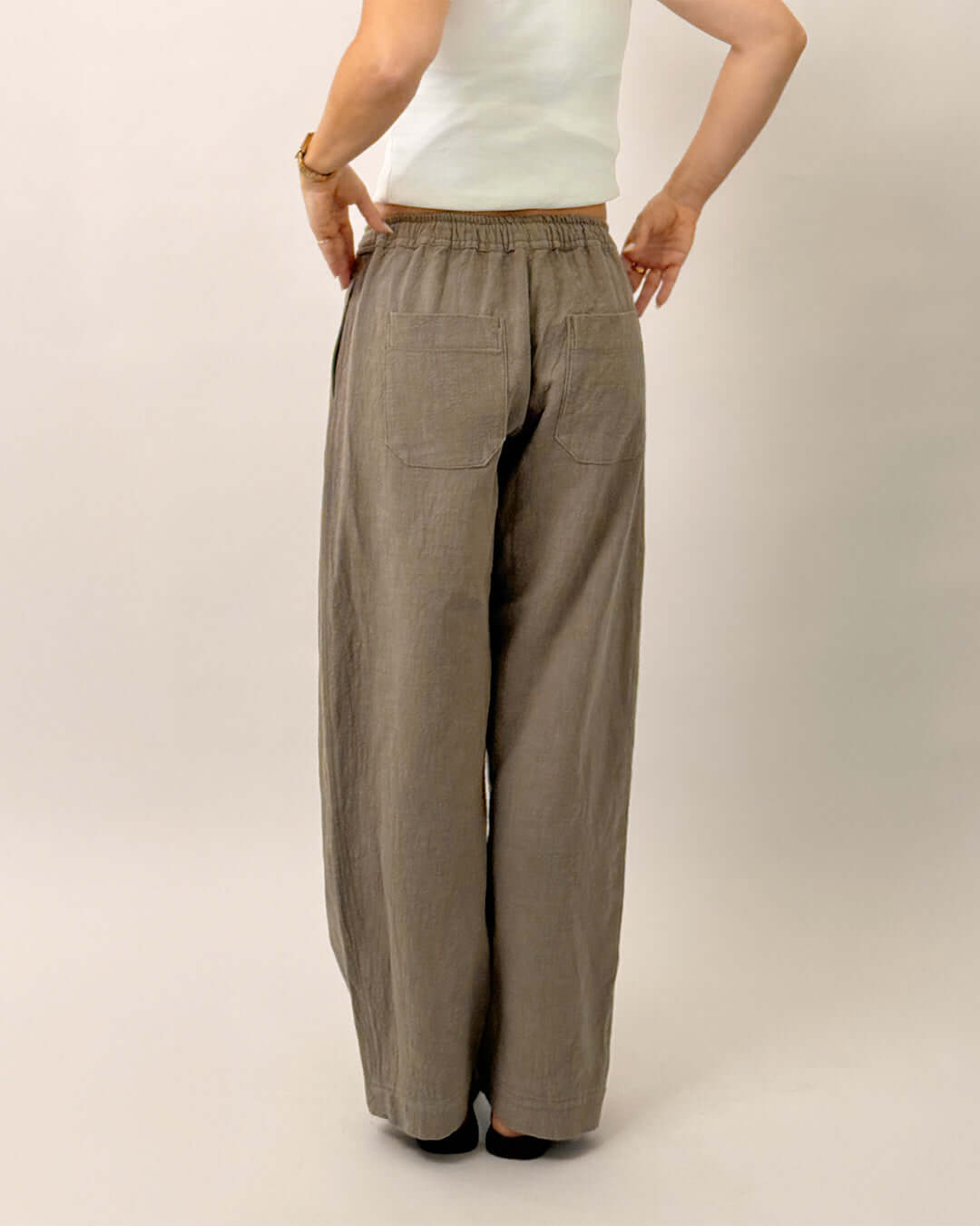 Back view of a person wearing Volume Pants Sewing Pattern in a light brown fabric, showcasing the elastic waist and pockets.