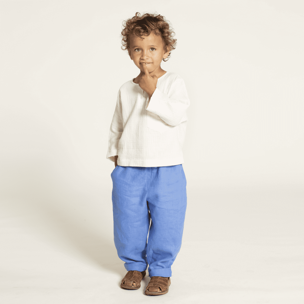 Kids' Volume Pants sewing pattern on a child, showcasing a playful look with a white top and blue pants.