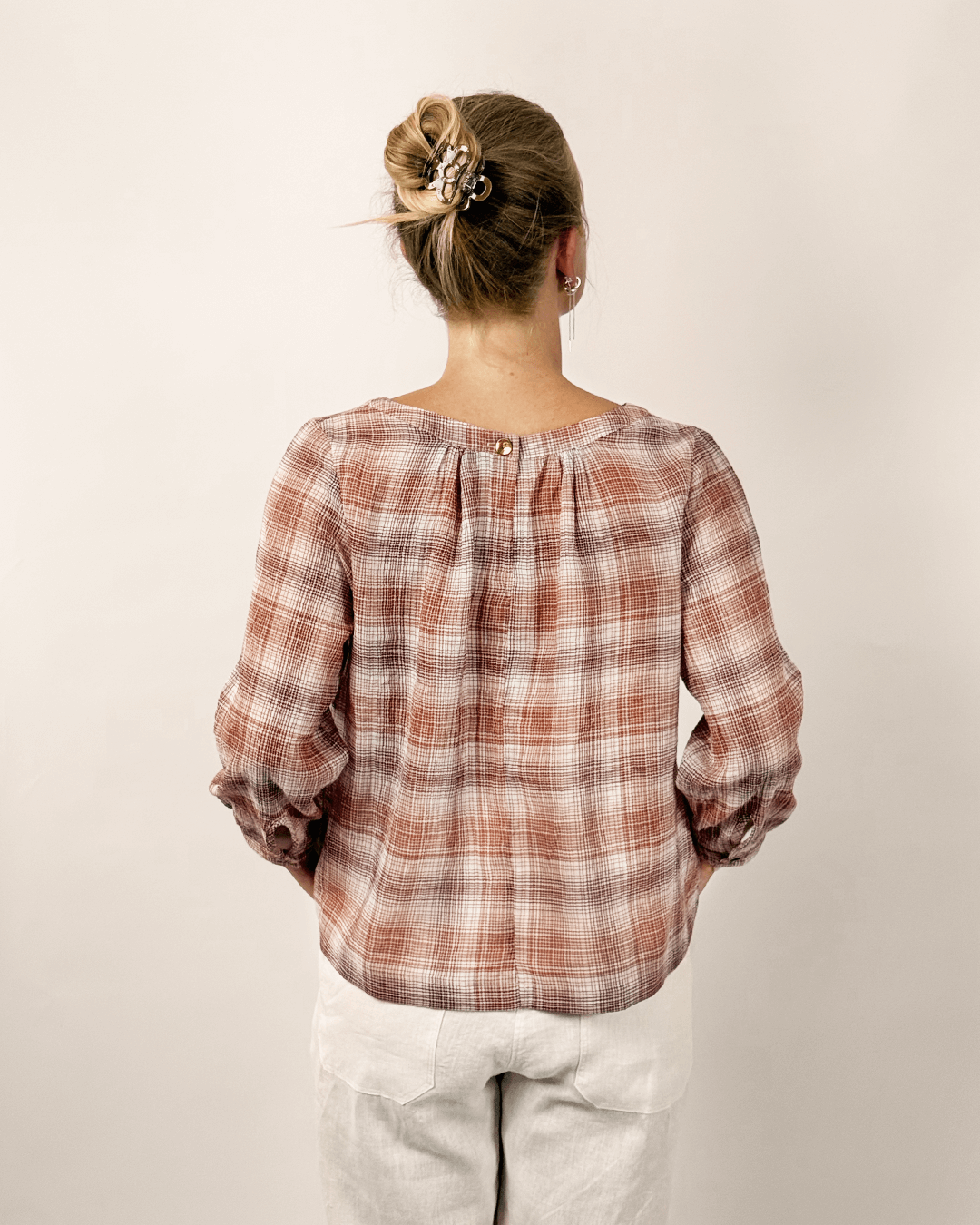 Back view of the Esther Blouse Paper Pattern showcasing button detail and gathered sleeves in a stylish woven fabric.
