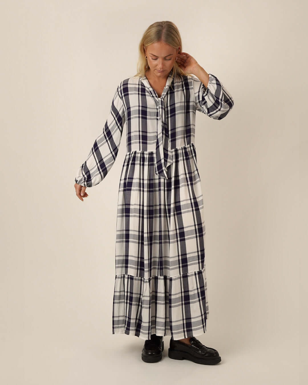 Woman wearing a black and white checkered freedom dress sewing pattern on a beige background
