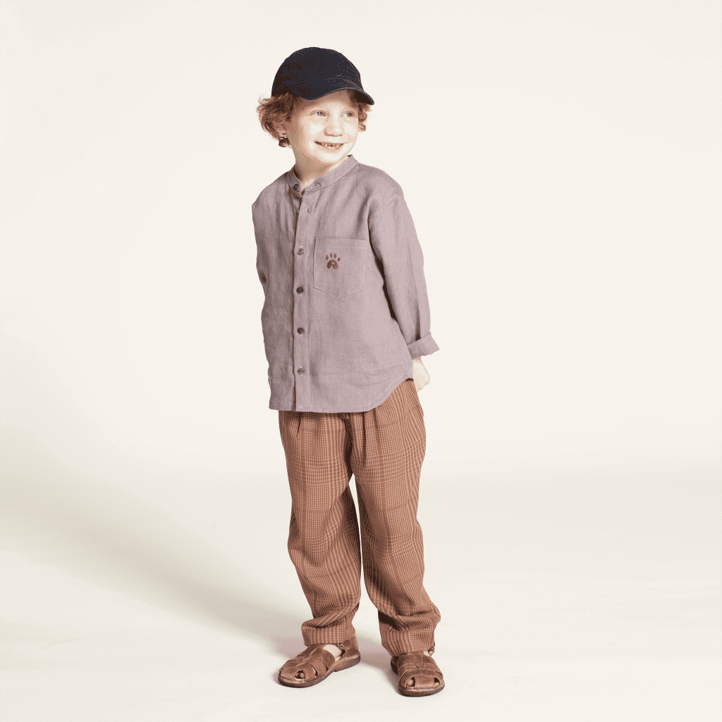 Child wearing a Mini Jensen Shirt Sewing Pattern styled with the kids Volume Pants sewing patternt, standing happily in casual outfit.