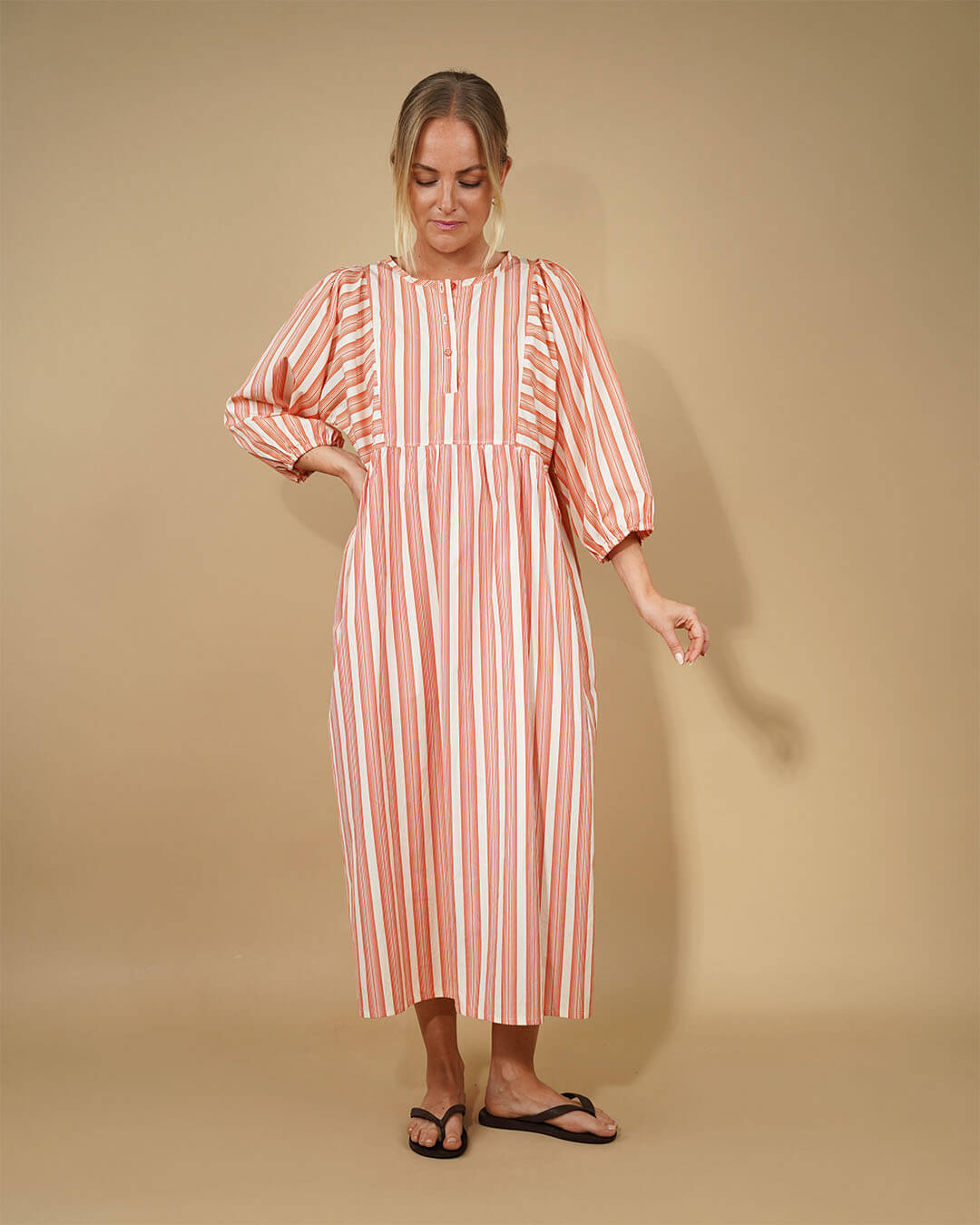 Woman wearing a striped Balka Dress sewing pattern dress against a beige background