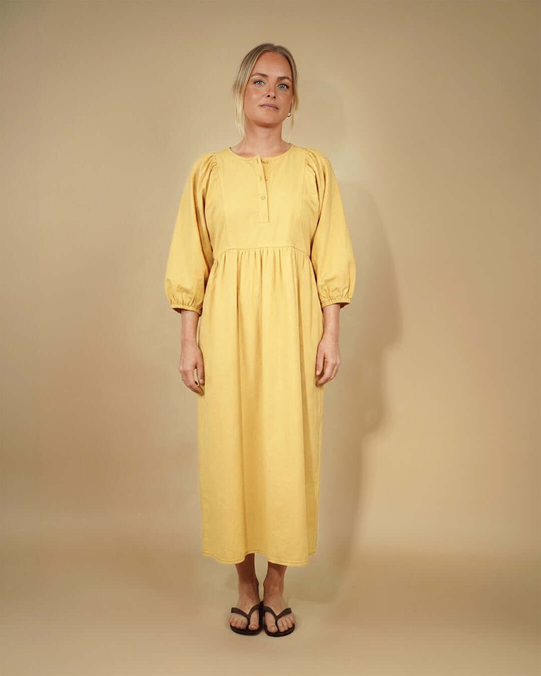 Woman wearing a yellow Balka dress sewing pattern against a beige background