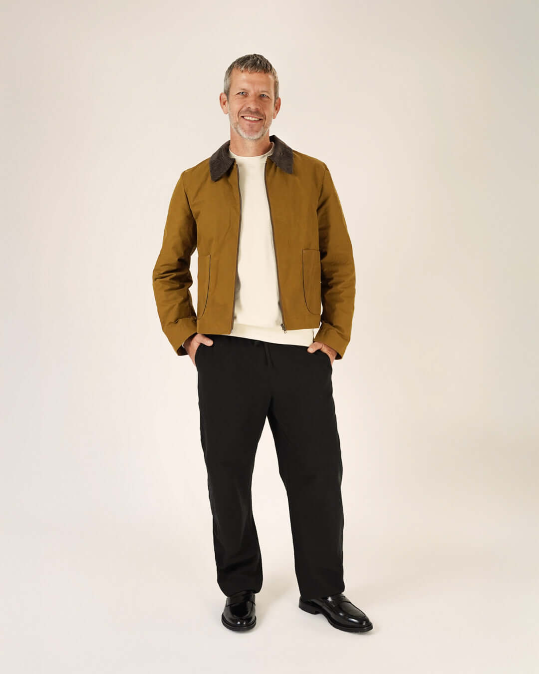 Man wearing a brown jacket and black Volume Pants Sewing Pattern, showcasing unisex pull-on pants.