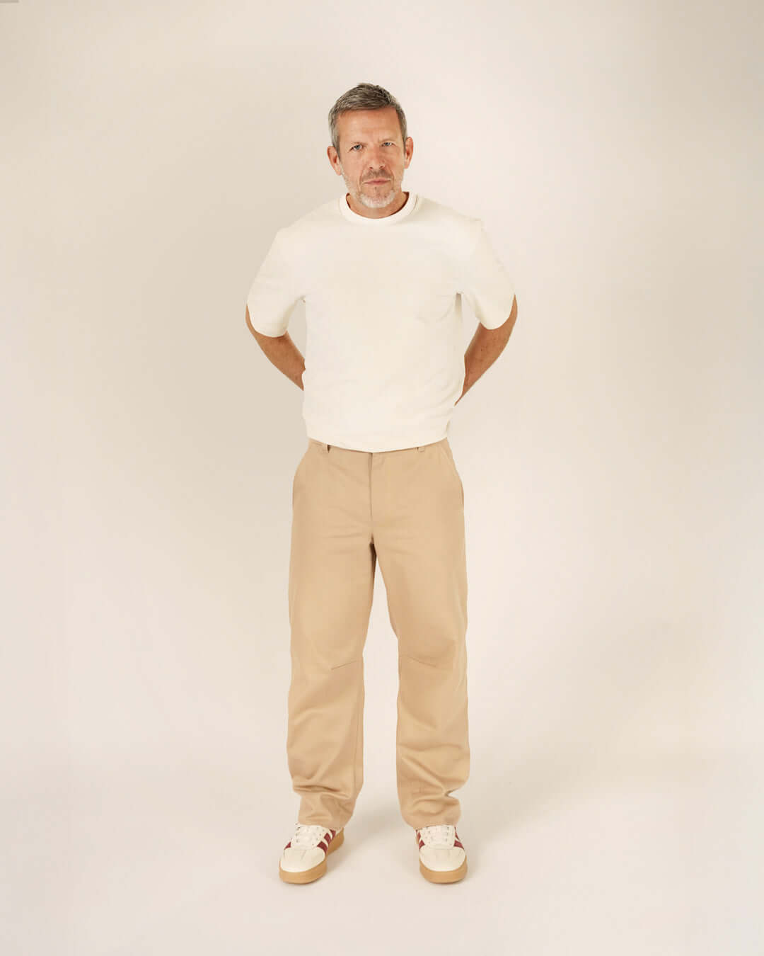 Man wearing a relaxed Big T-shirt sewing pattern in white with beige trousers, showcasing modern style and comfort.