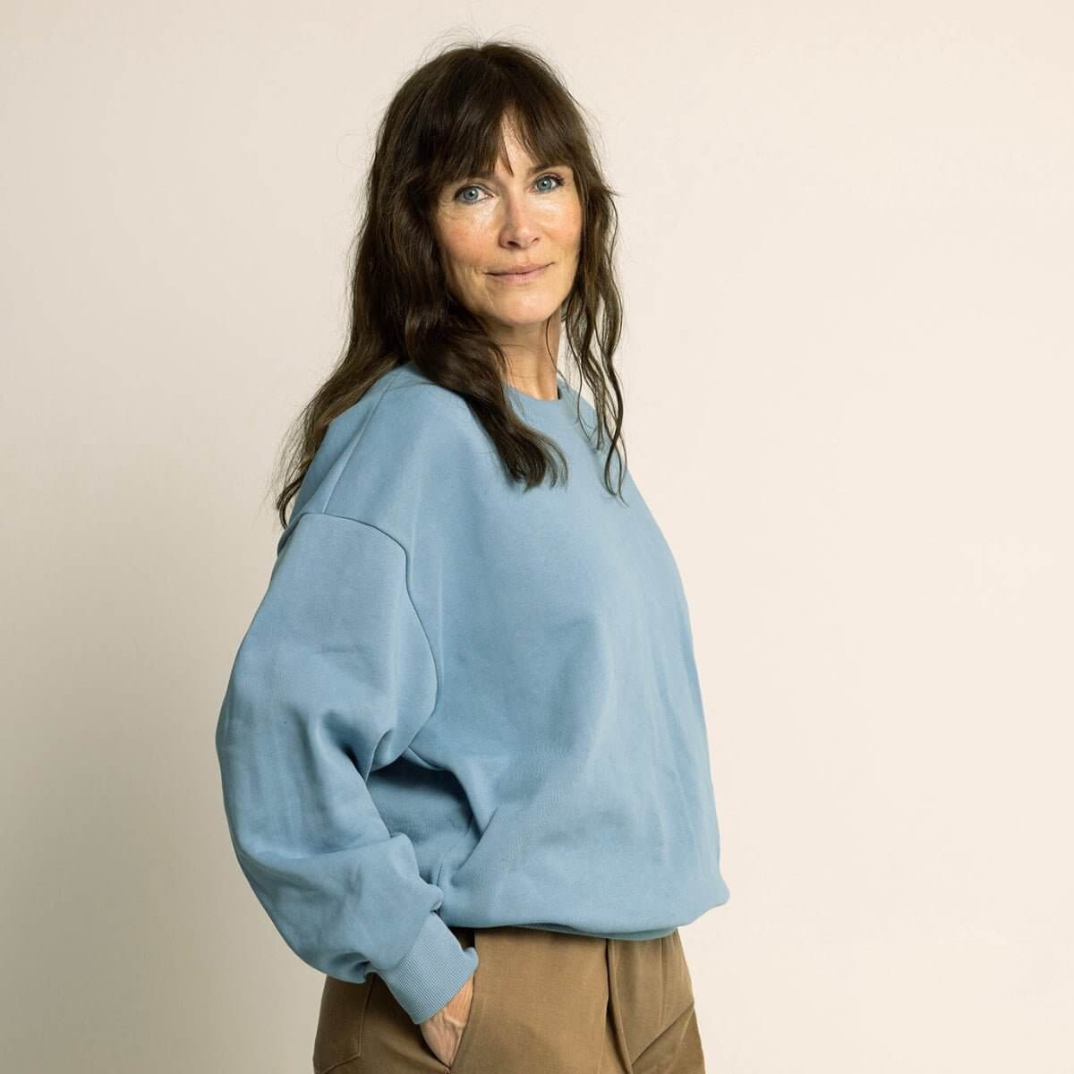 Woman wearing a cozy oversized outfit featuring the Boyfriend Sweater Paper Pattern in soft blue color.