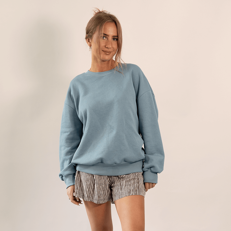 Model wearing a blue oversized sweater and striped shorts showcasing comfort and style of the Boyfriend Sweater Paper Pattern.