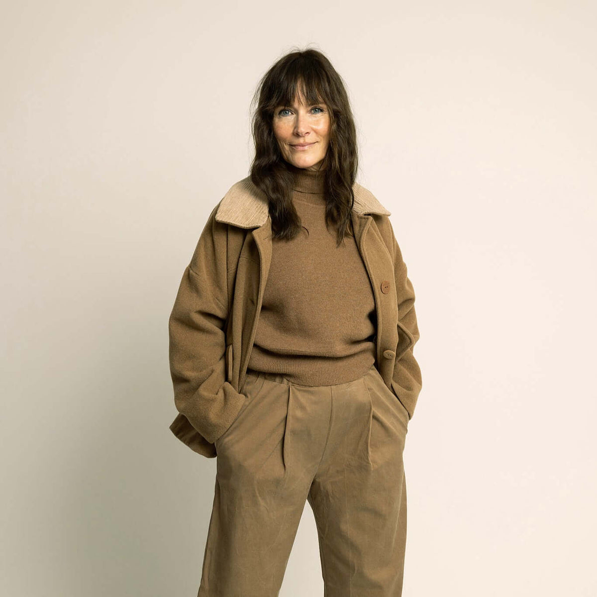 Car Coat Sewing Pattern Wardrobe By Me model wearing a stylish brown car coat with a warm sweater and high-waisted trousers.