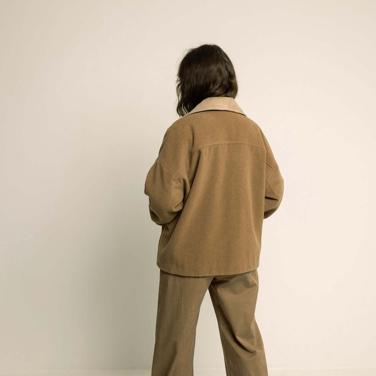 Back view of a model wearing a Car Coat Sewing Pattern in brown, showcasing its relaxed fit and style.