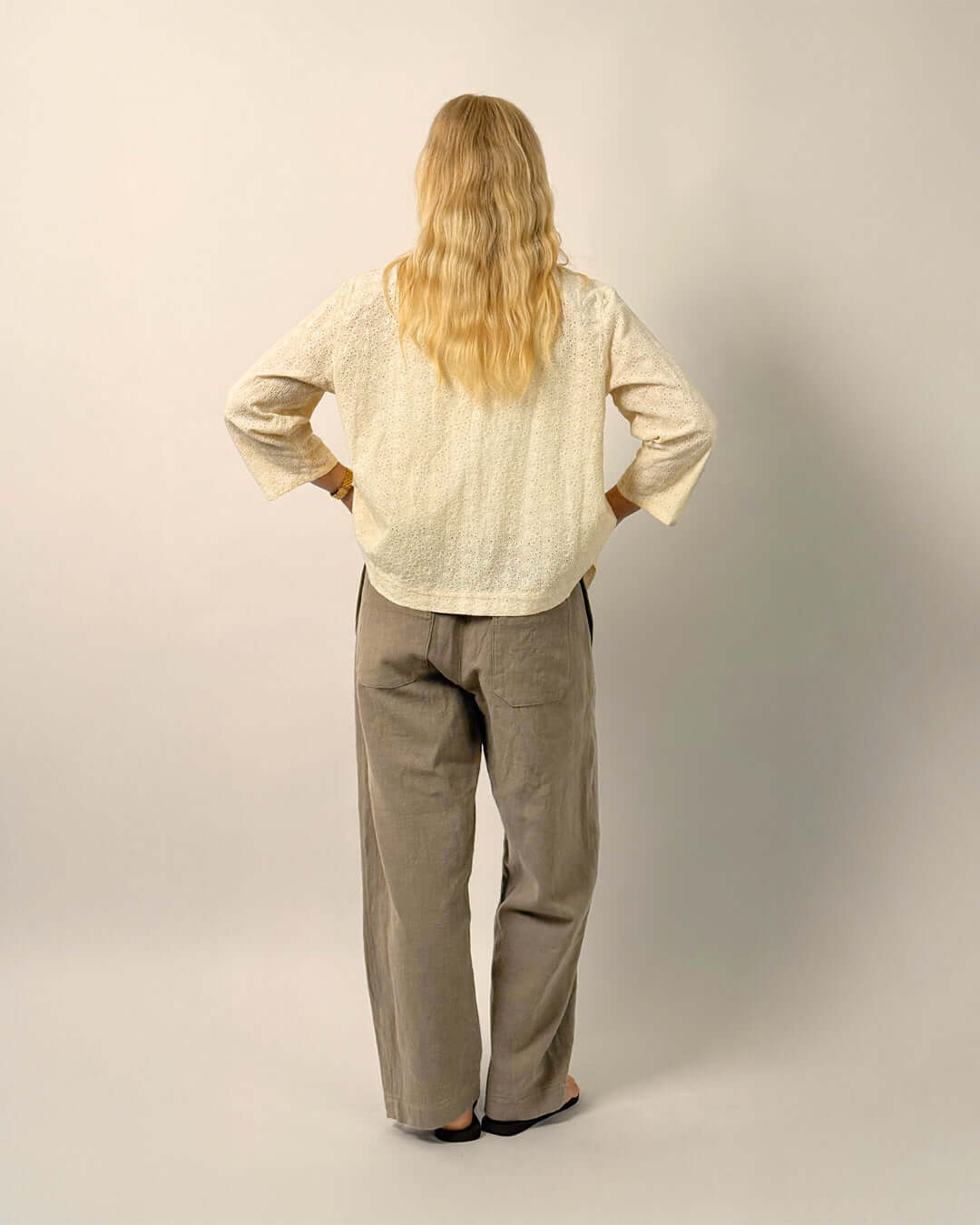 Back view of a woman wearing the Dukke Blouse Paper Pattern with relaxed-fit and 3/4-length sleeves.