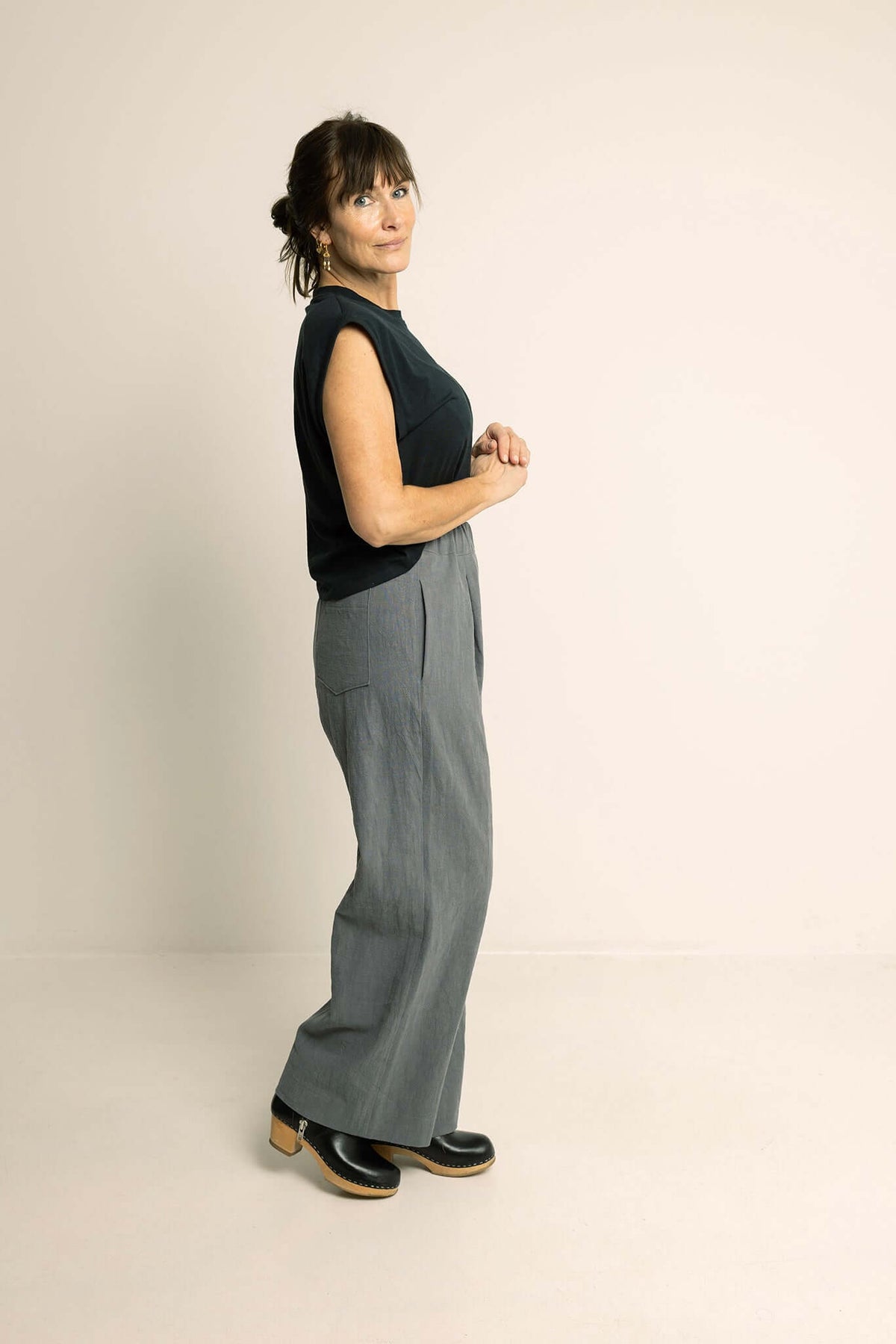 Woman wearing Palazzo Pants Paper Pattern with wide legs and pockets, styled with a black top and clogs.