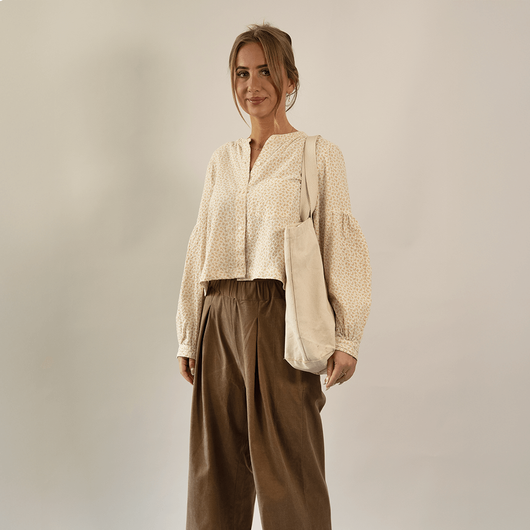 Model wearing Palazzo Pants Paper Pattern with wide legs, paired with a patterned blouse and a tote bag.