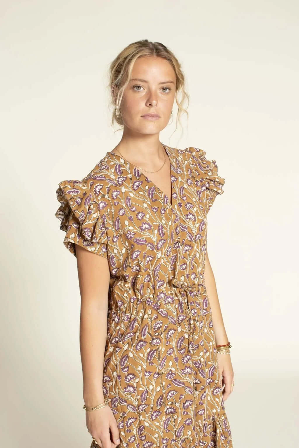 Model wearing the Abby Dress sewing pattern featuring ruffled sleeves and a deep V-neckline, showcasing a floral design.