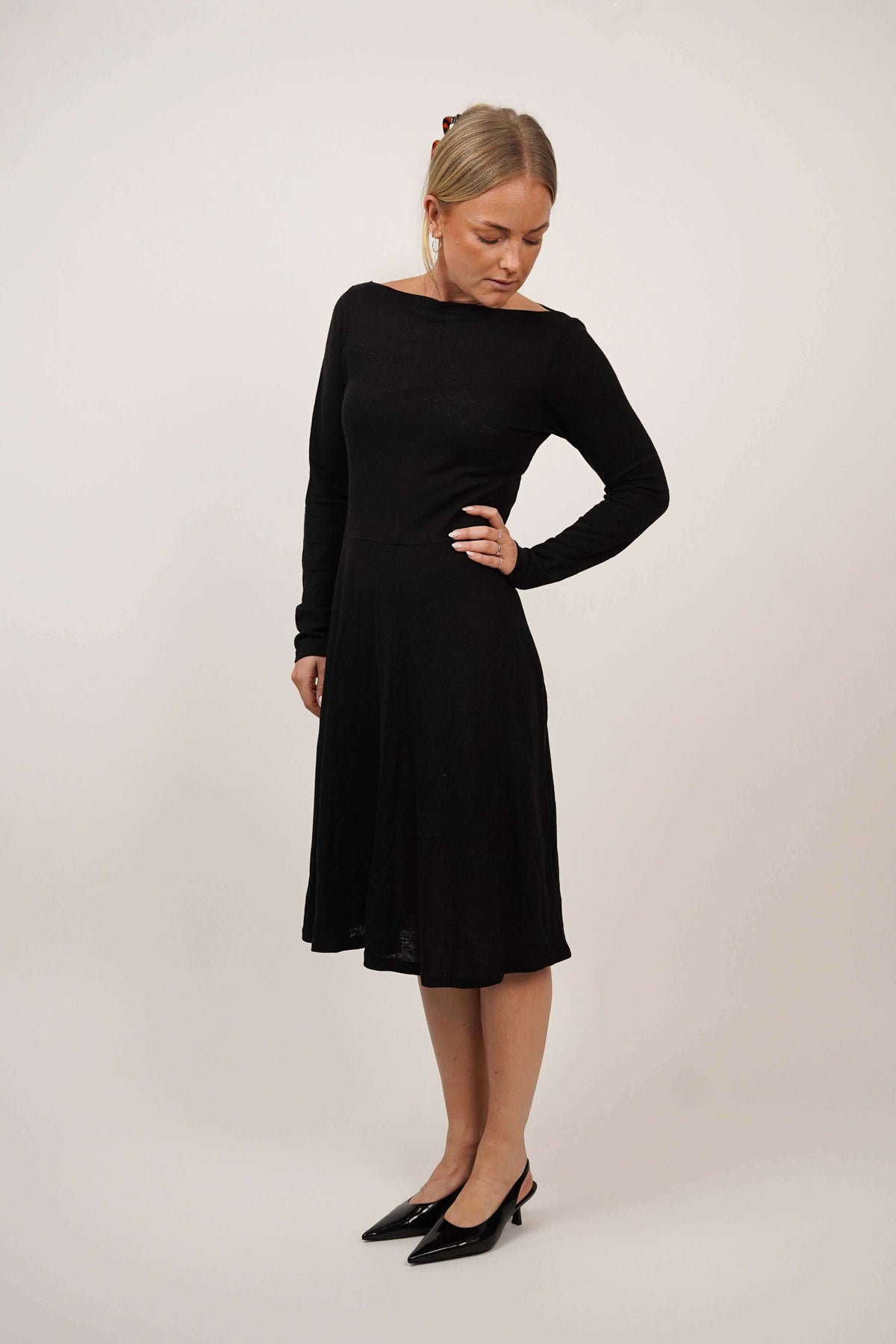 Woman wearing the Asta Dress sewing pattern in black jersey, shown from a three-quarter side angle