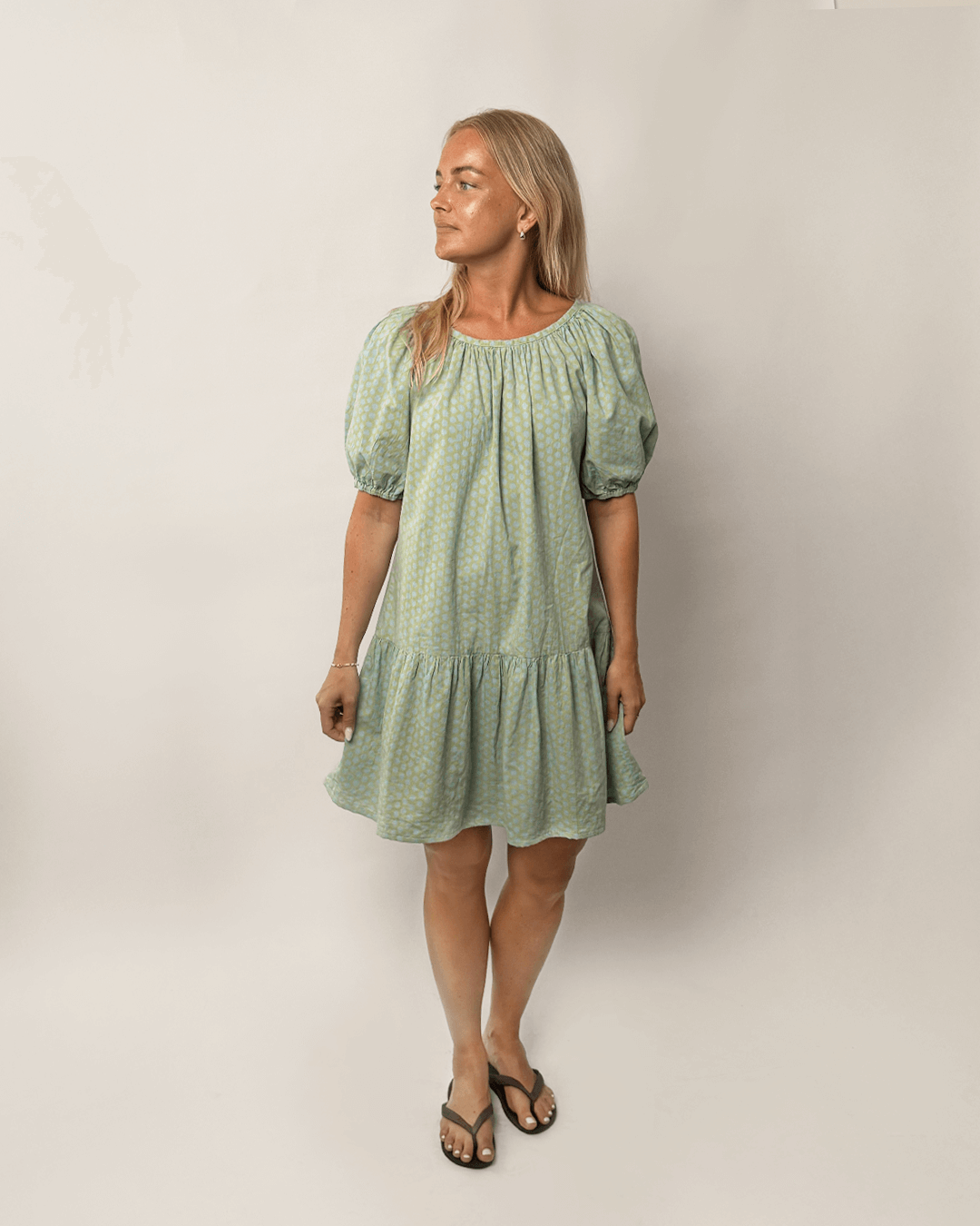 Woman wearing a green dress with puff sleeves against a plain background