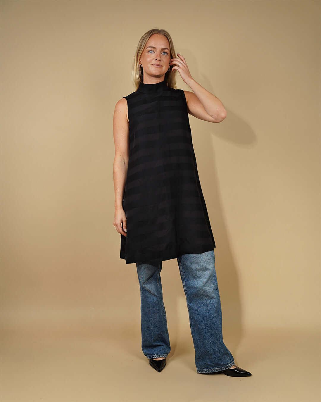 Woman wearing a black sleeveless dress with a high neck, showcasing the June Dress Sewing Pattern.