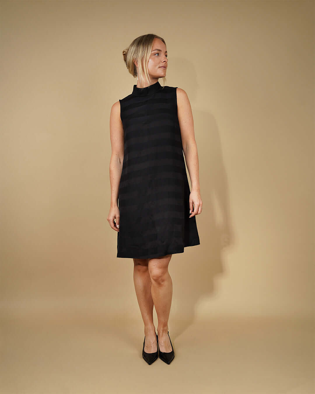 Woman wearing a black sleeveless dress, showcasing the June Dress Sewing Pattern with A-line silhouette.