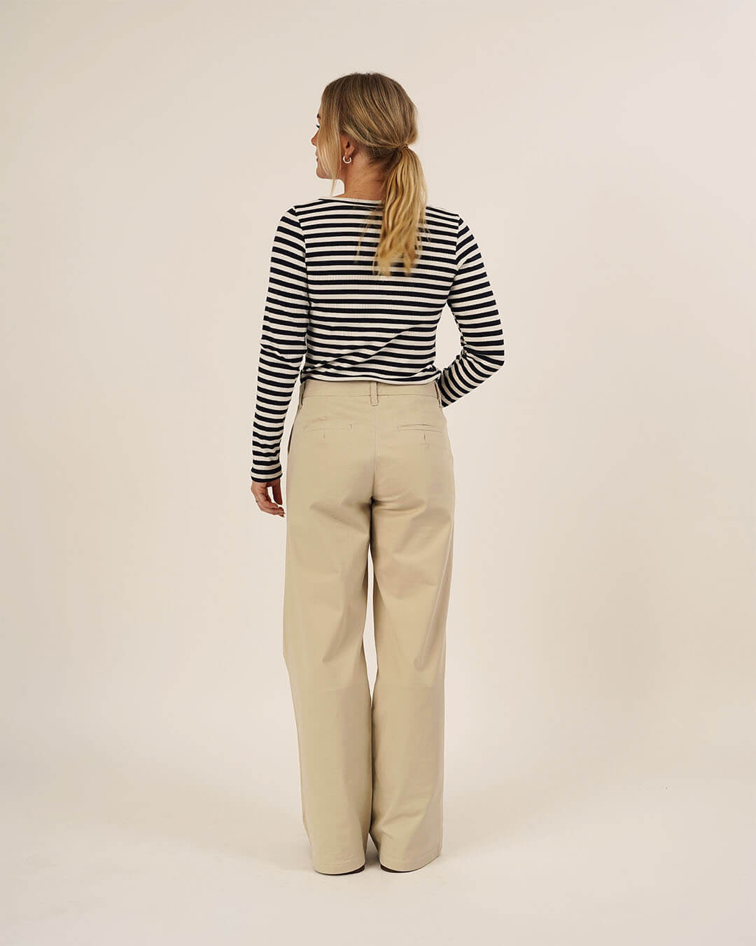 Woman wearing the Wardrobe Builder T-shirt sewing pattern in black and white striped knit paired with Hepburn Pants in beige cotton twill, shown from the back