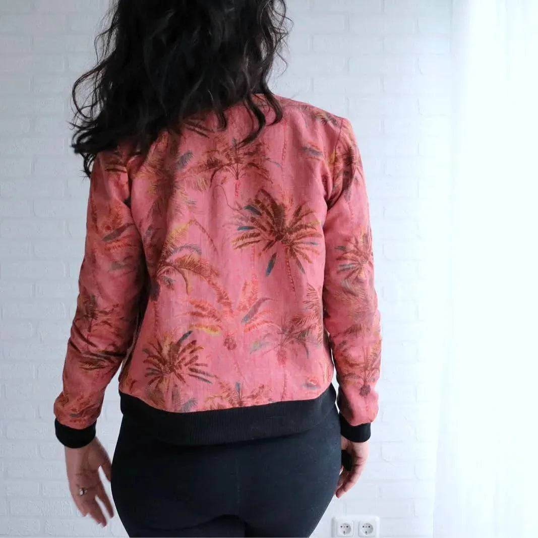 Woman modeling a pink bomber jacket featuring a palm tree print, showcasing the Bomber Jacket Paper Pattern.