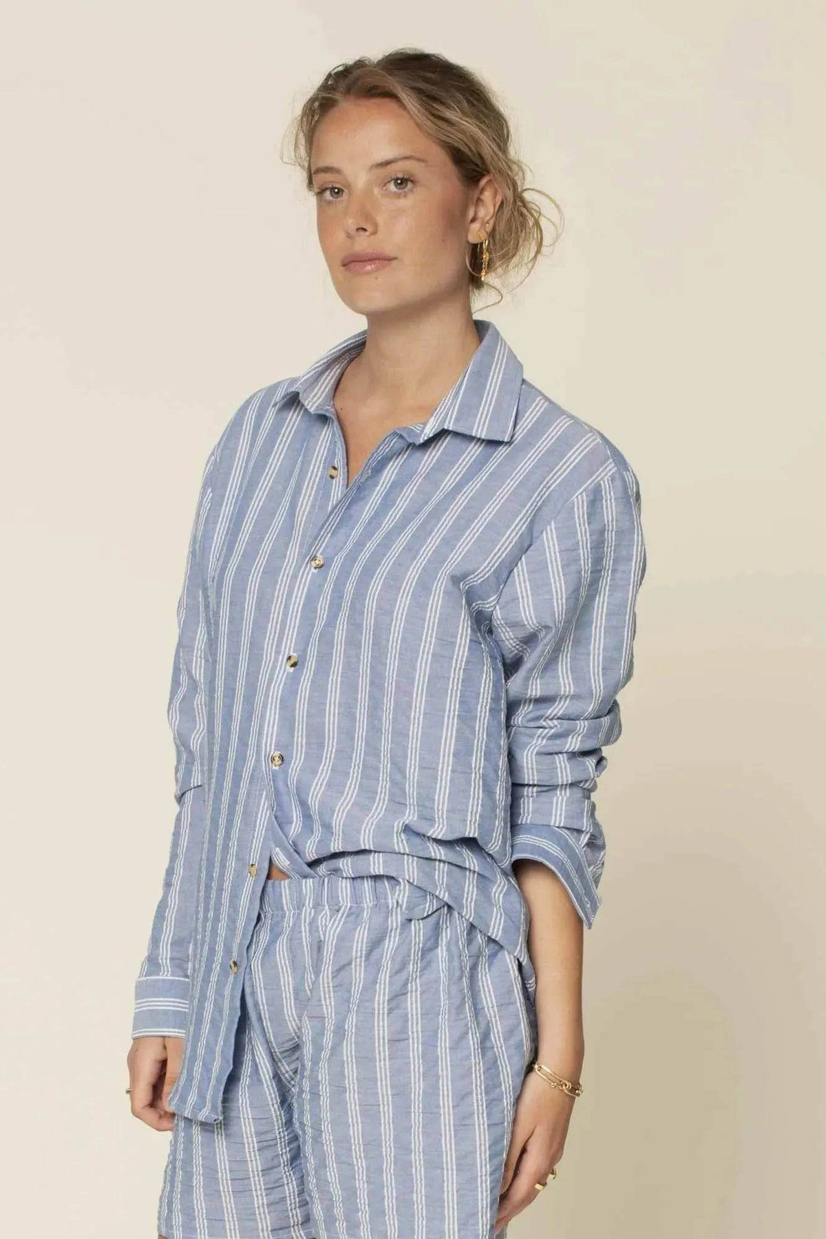 Anna Shirt Paper Pattern worn by a model, featuring a blue striped design and classic button-up style.