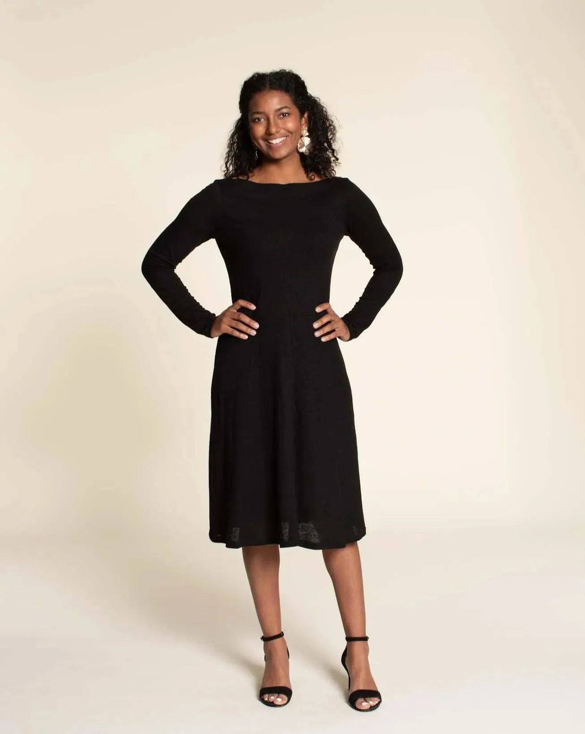 Asta dress Paper Pattern modeled by a woman, showcasing a fitted bodice and semi-circular A-line skirt in black.