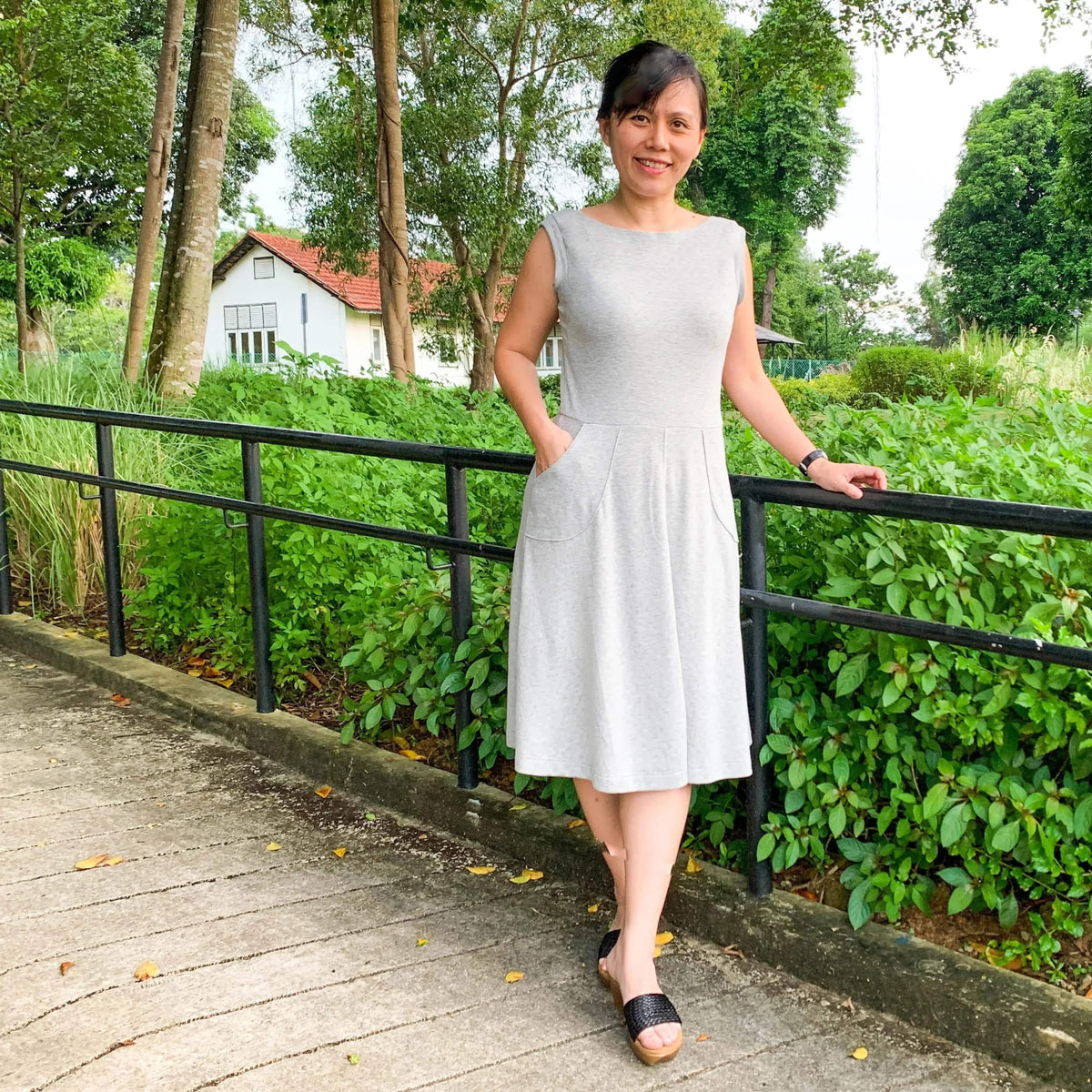 Asta dress Paper Pattern modeled by a woman standing outside in a grey knit dress with pockets.