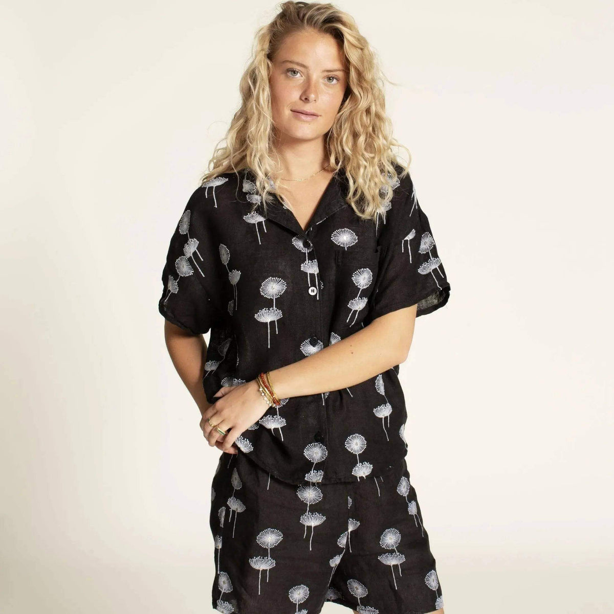 Woman wearing a Camp Shirt and shorts Paper Pattern in black fabric with floral prints.
