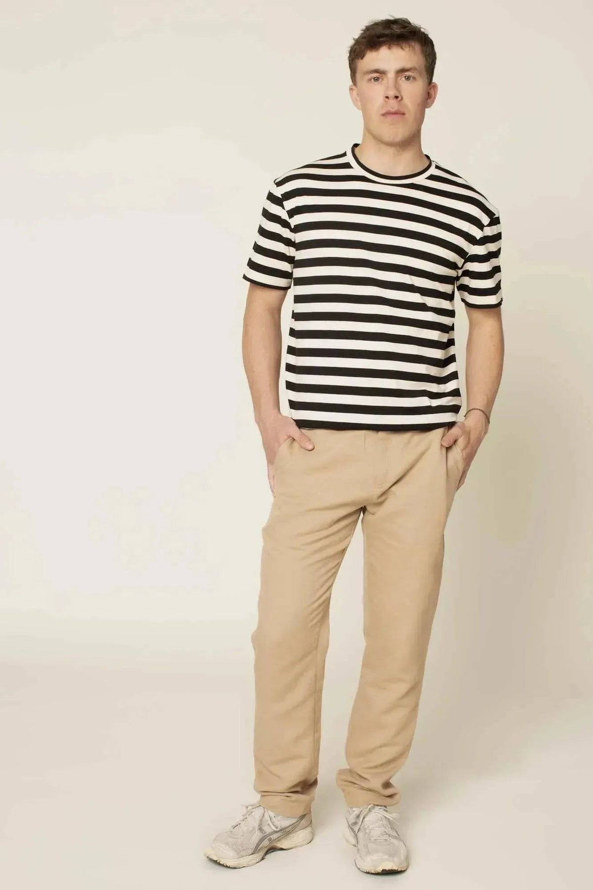 Man wearing Chino Pants Paper Pattern with a striped t-shirt in a neutral background.