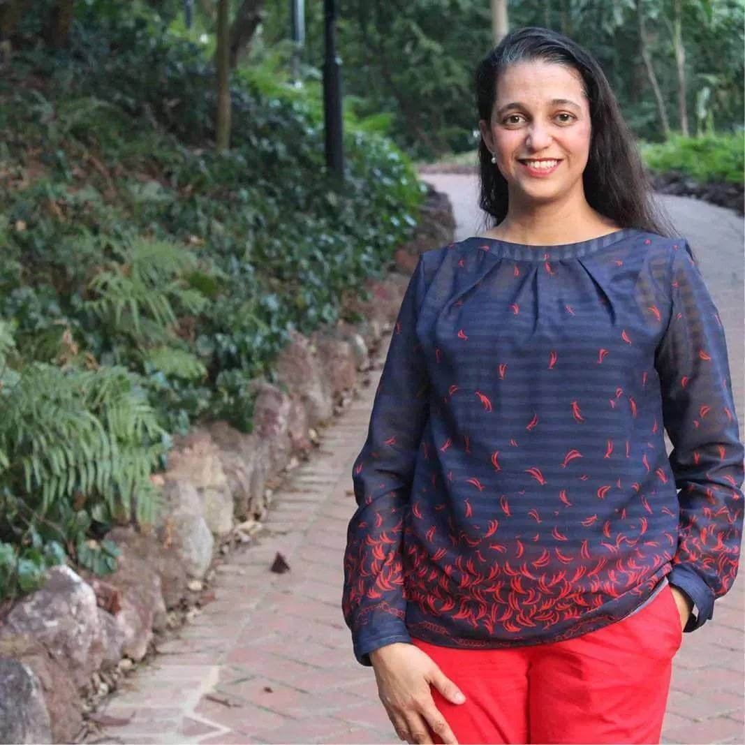 Esther Blouse Paper Pattern modeled by a woman in a navy blouse with red accents, showcasing the feminine design.