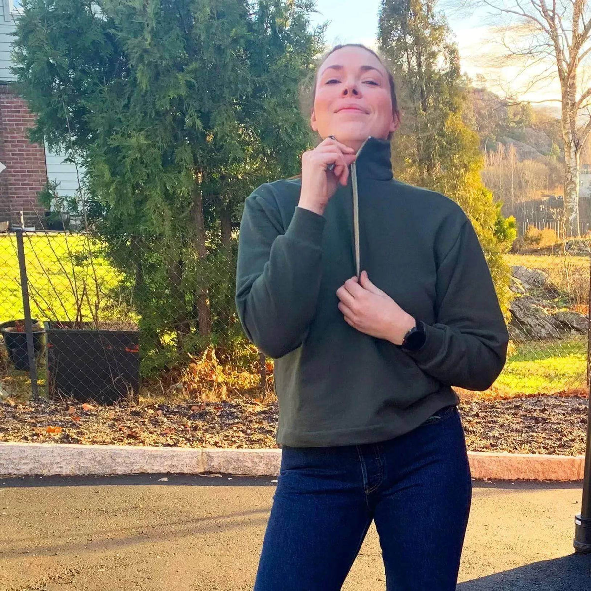 Woman modeling a Half-Zipper Sweater Paper Pattern in green with a sporty collar outdoors.