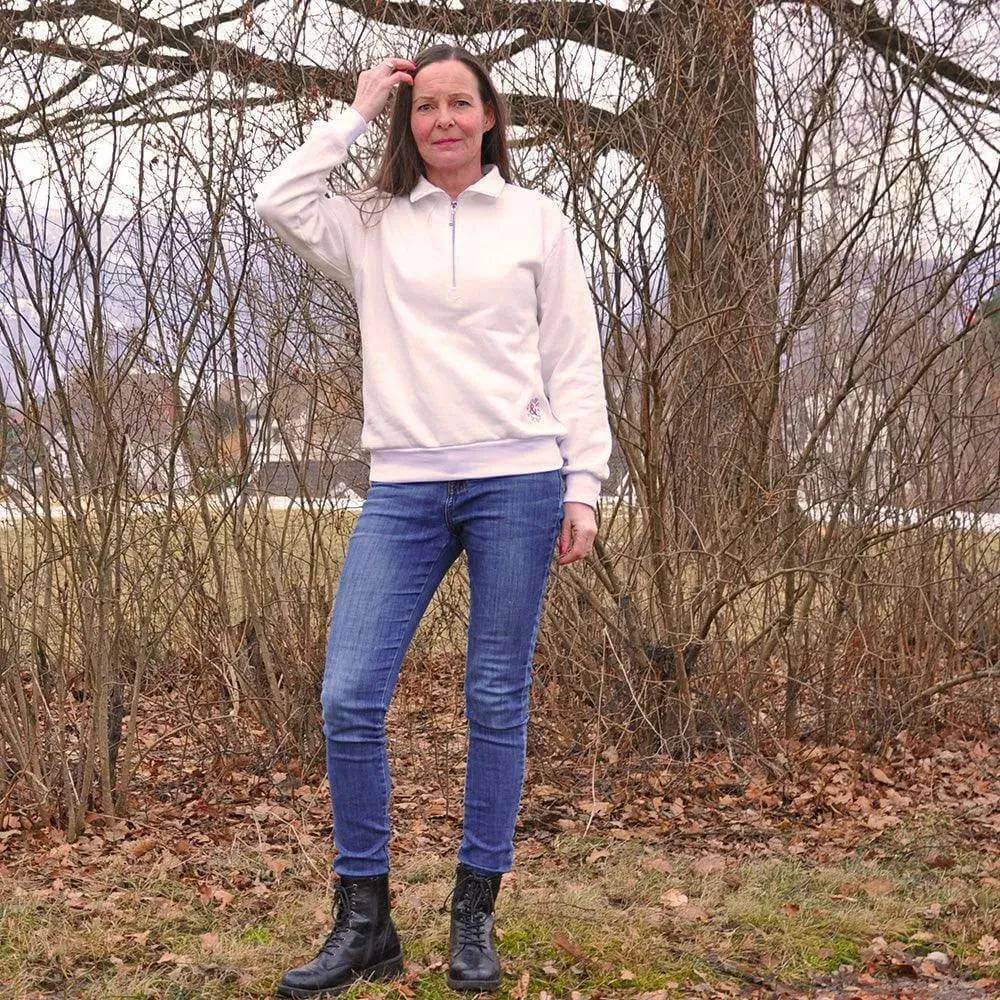 Woman wearing a Half-Zipper Sweater Paper Pattern in a natural outdoor setting with jeans and boots.