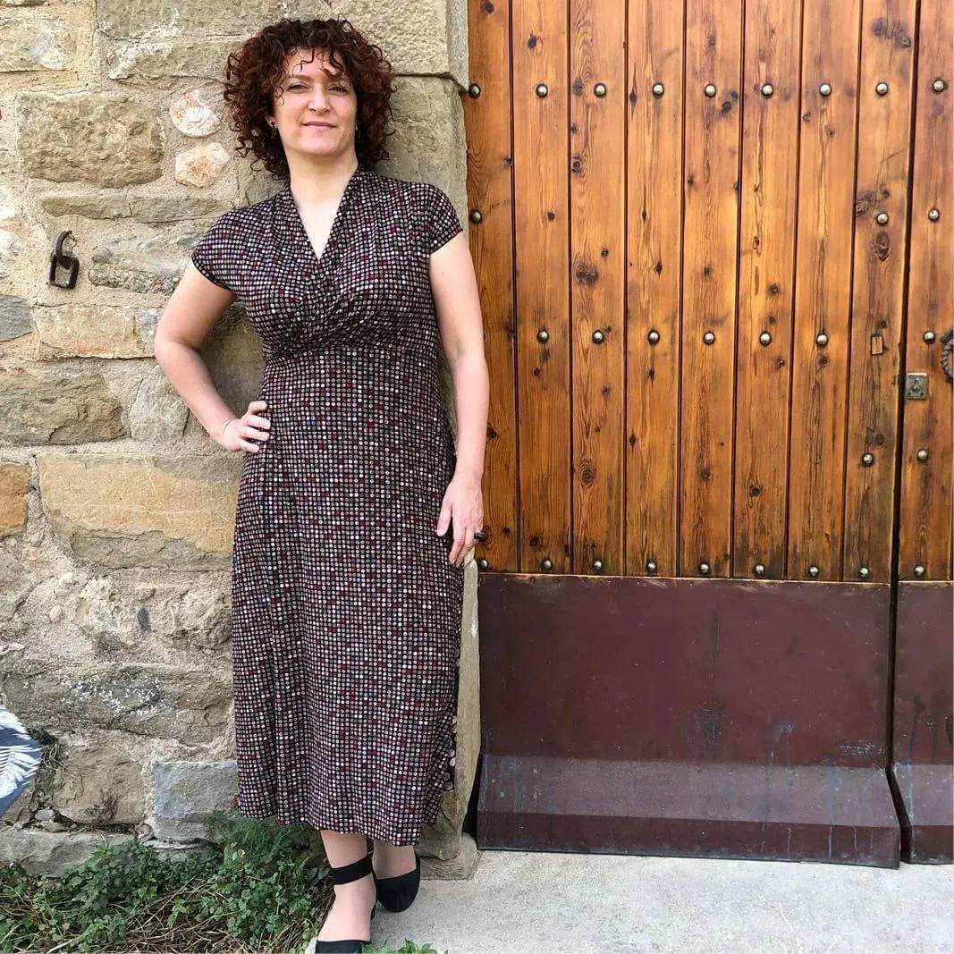Mirri Dress Paper Pattern model wearing a fitted dress with shawl collar standing by wooden door.
