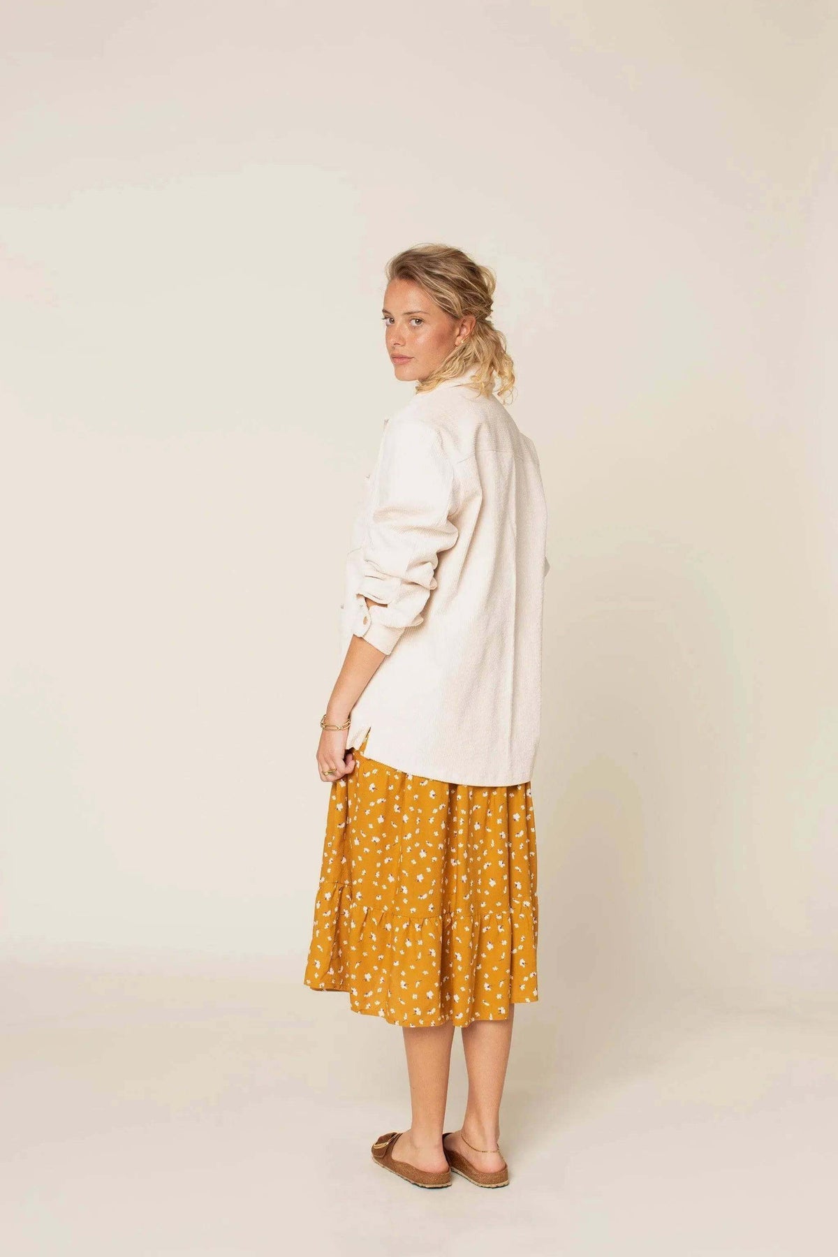 A woman wearing an Overshirt Jacket Paper Pattern with a yellow polka dot skirt, showcasing a stylish back view.