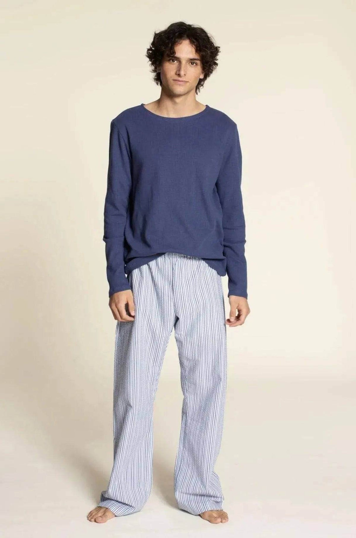 Man wearing Pajama Pants Paper Pattern with a blue sweater and striped pajama pants, showcasing comfort and style.