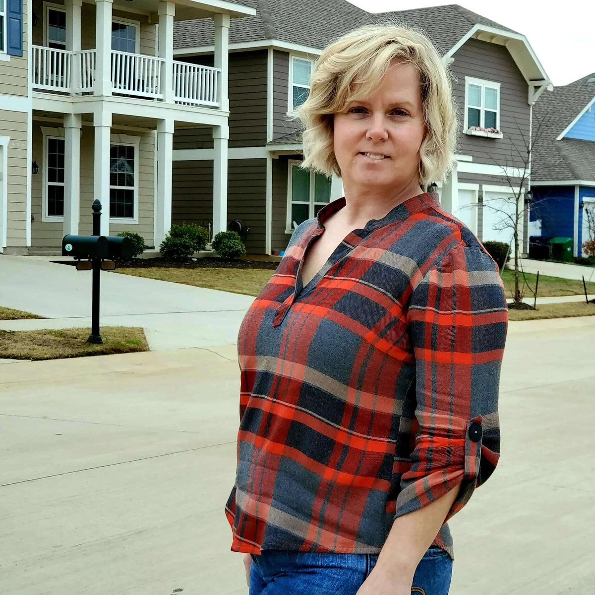 Woman wearing a plaid top standing on a residential street; showcasing the Perfect Tunic Paper Pattern.