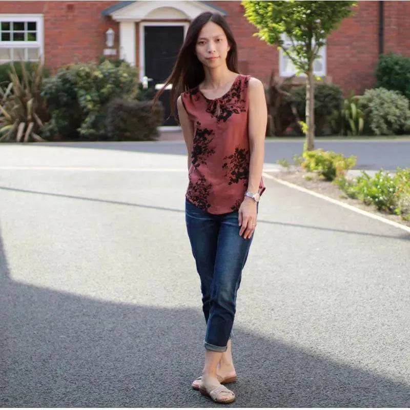 Woman wearing Piper Tunic Paper Pattern in floral design, walking in a picturesque outdoor setting.