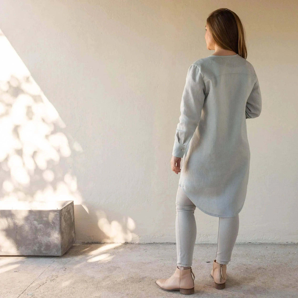 Savannah shirt Paper Pattern styled as a long shirt dress in light grey, paired with fitted pants and ankle boots.