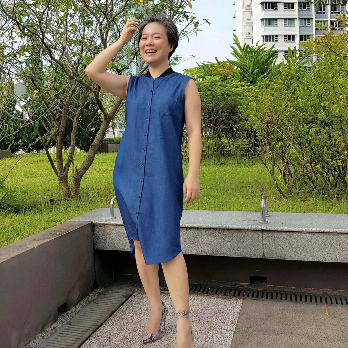 Woman wearing a Savannah shirt Paper Pattern denim dress in an outdoor setting, showcasing a stylish and versatile look.