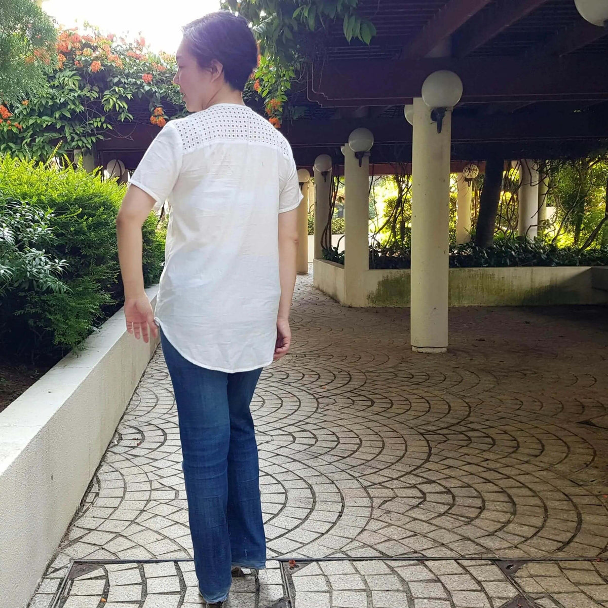 Woman wearing the Savannah shirt Paper Pattern in a garden setting, showcasing the elegant design and casual fit.