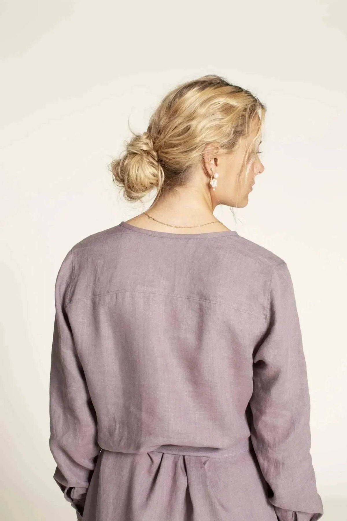 Back view of woman wearing the Savannah shirt Paper Pattern in a soft purple fabric, showcasing minimalistic style.