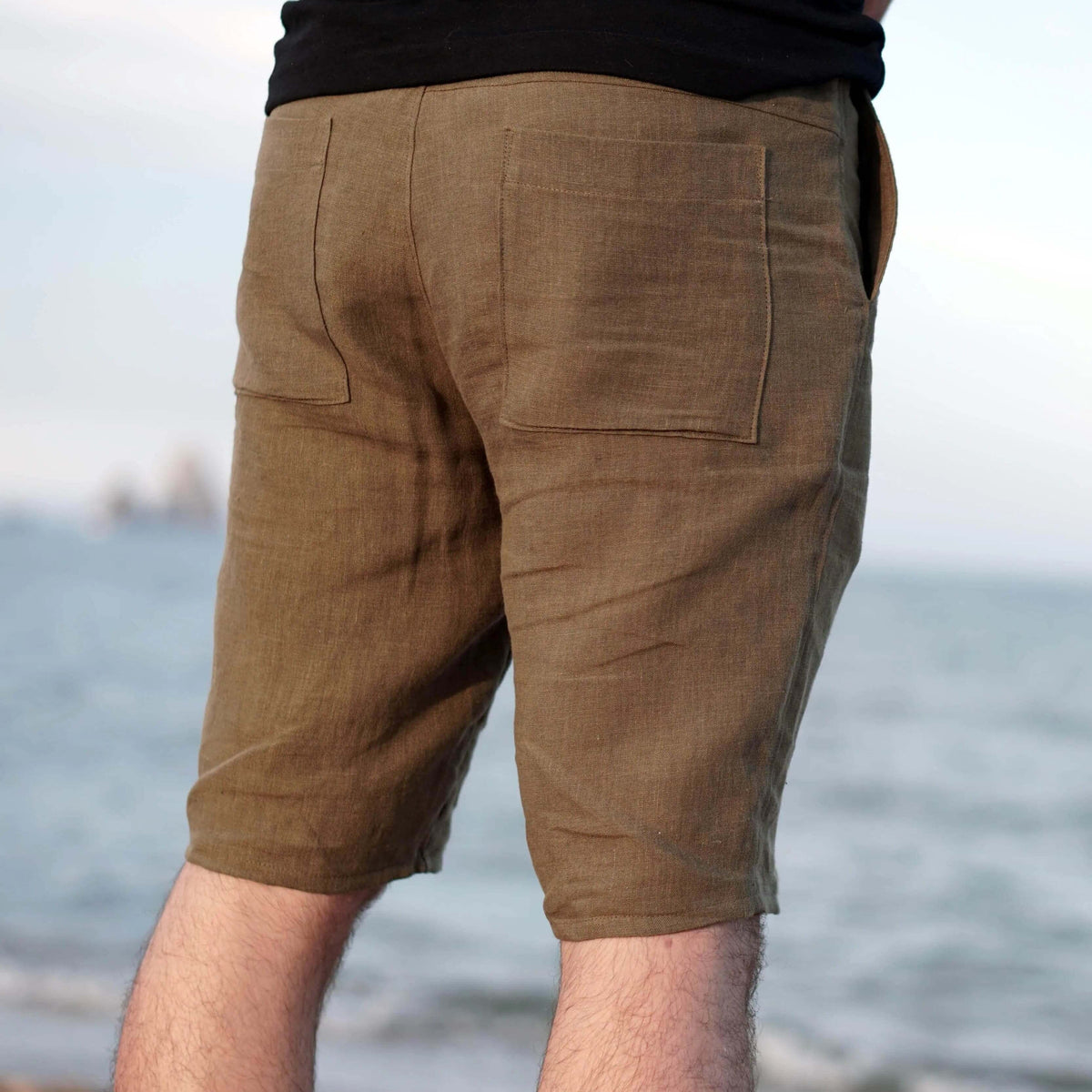 Men's Summer pants paper pattern showing back view of lightweight casual shorts at the beach.