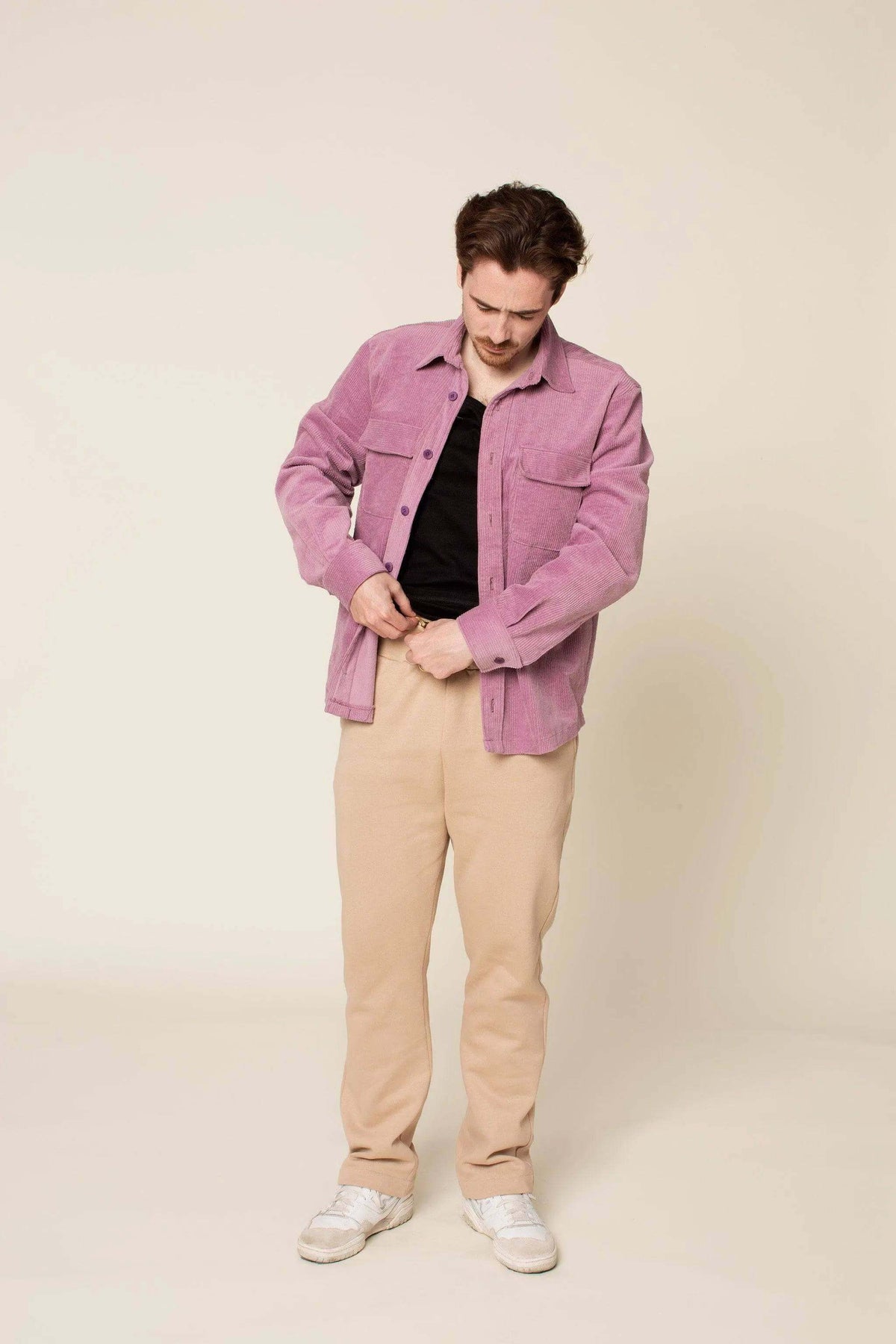 Man wearing a purple shirt and beige pants with a relaxed fit, showcasing the Rebel Sweatpants Paper pattern style.
