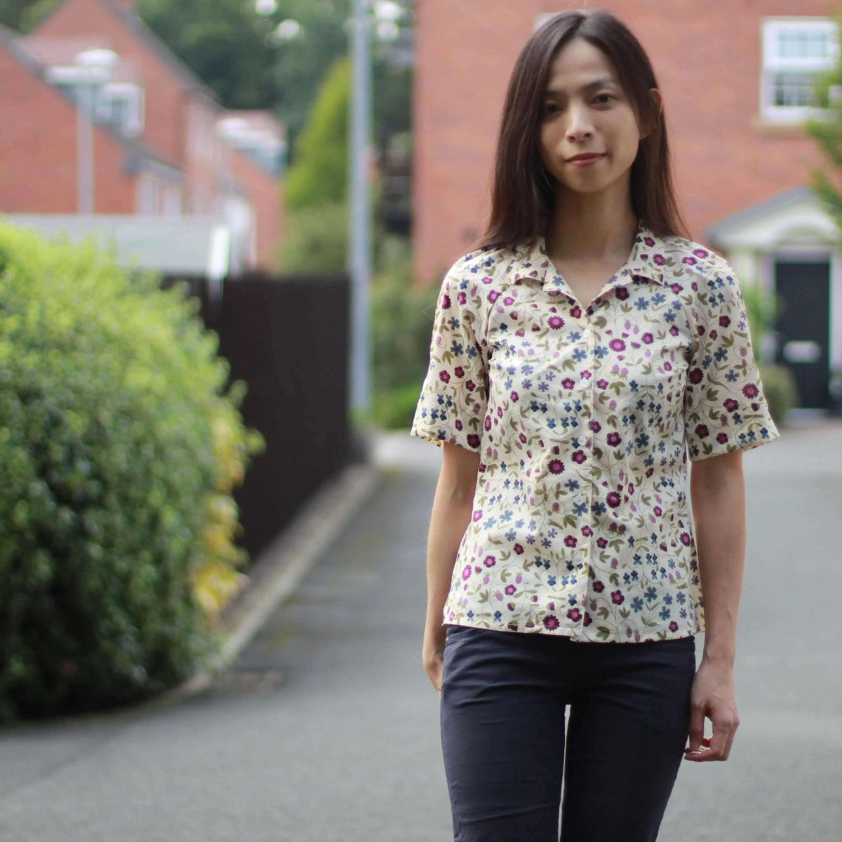 Model wearing a floral Tropicana Shirt Paper Pattern with short sleeves on a street.